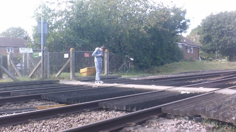 Záběry ukazují, že teenager stál uprostřed železničního přechodu a zíral na jeho telefon. Pic: National Rail