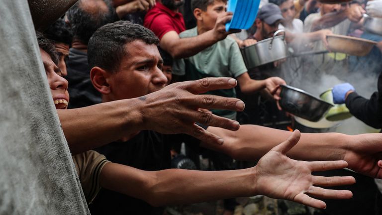 Palestinci dostávají jídlo z charitativní kuchyně.  Pic: Reuters/Mahmúd Issa