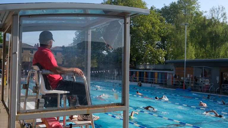 Životní strážce sedí ve stánku, když lidé plavou ve venkovním bazénu, protože se očekává, že teploty dosáhnou 27 stupňů Celsia, v London Fields Lido ve východním Londýně v Británii 1. května 2025. Reuters/Vitalii Yalahuzian