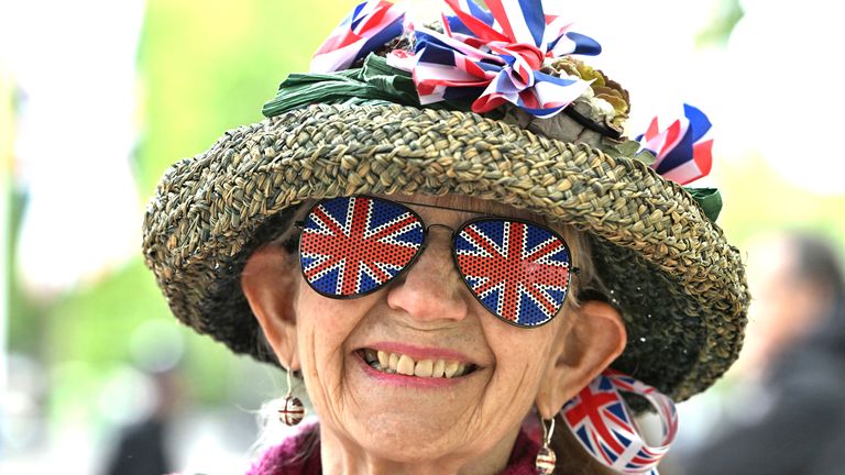Žena nosí náušnice, klobouky a stuhy britské vlajky, klobouk a stuhy, když zaujme své místo v obchoďáku, aby čekala na přehlídku 80. výročí VE dne.  Pic: Ap