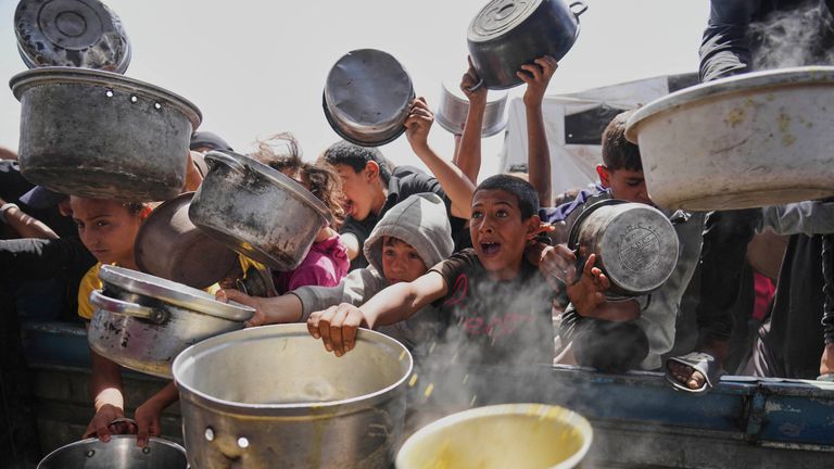 Palestinské děti se snaží získat darované jídlo v komunitní kuchyni v Khan Younis, Gaza Strip, sobotu 3. května 2025. (AP Photo/Abdel Kareem Hana)
