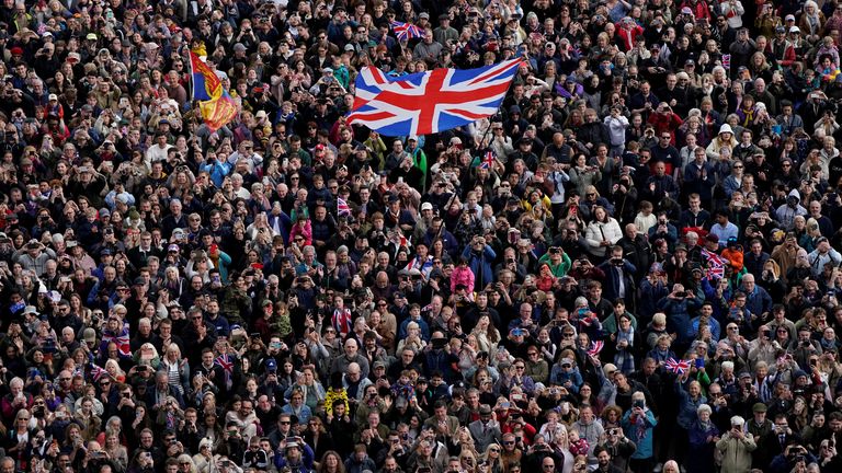 Osoba v davu mává vlajku Union Jack, jako členové veřejnosti chodí po obchoďáku poblíž Buckinghamského paláce v centru Londýna, po vojenském průvodu označujícím 80. výročí VE dne, a na počest těch, kteří sloužili během druhé světové války, v centru Londýna, 5. května 2025. Andrew Matthews/bazén