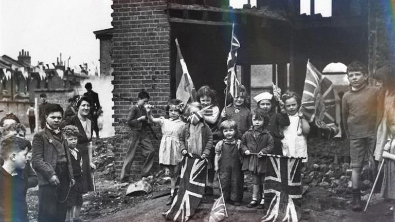 Děti mávají vlajky z ruin jejich domovů v Battersea v jižním Londýně. Když oslavují den. Pic: Pa