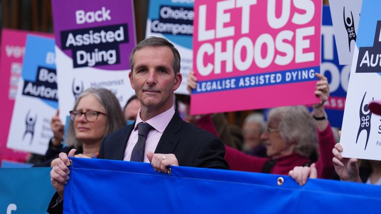 Liberální demokrat MSP Liam McArthur (centrum) stojí s příznivci změny zákona o asistovaném umírání mimo skotský parlament v Edinburghu, před debatou a hlasováním o asistovaném umírání pro terminálně nemocné dospělé (Skotsko) později dnes. Datum obrázku: Úterý 13. května 2025.
