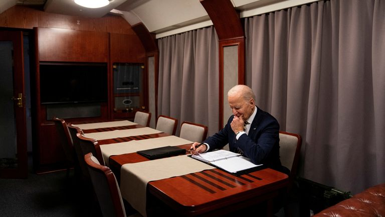 Prezident Joe Biden sedí ve vlaku, když po překvapivé návštěvě ukrajinského prezidenta Volodymyr Zelenskiyho v Kyjevě prochází jeho řeč a označuje jednoleté výročí války na Ukrajině. Evan Vucci/Pool přes Reuters