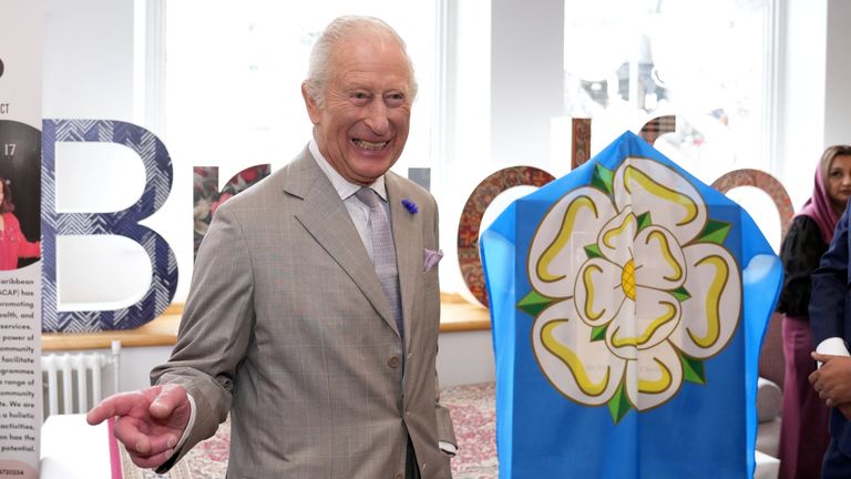 Král Charles stojí vedle vlajky Yorkshire, když navštěvuje Impact Hub Yorkshire v Bradfordu