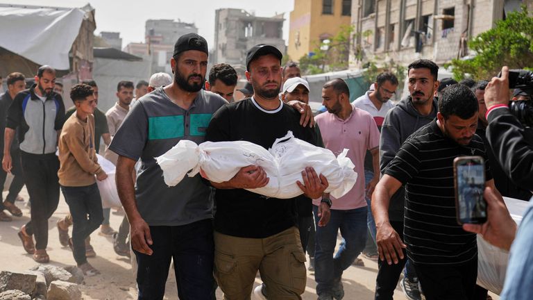 Saleh Zenati, nese tělo svého kojeneckého synovce Khalida Zenatiho zabitého v izraelské armádě, během jeho pohřbu v Khan Younis, Gaza Strip, neděle 18. května 2025. (AP Photo/Abdel Kareem Hana)