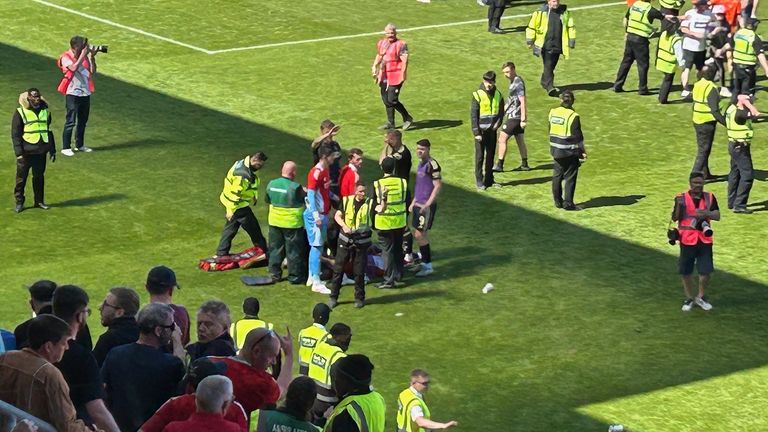 Aberdeen's Jack Mackenzie dostane léčbu na hřišti, když fanoušci napadnou hřiště po vítězství Dundee United nad Aberdeenem v Tannadice Parku v Dundee. Datum obrázku: Sobota 17. května 2025. Ronnie Esplin/PA Wire