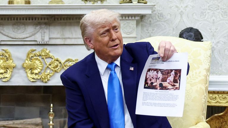 Prezident Trump drží vytištěnou kopii blogu. Obrázek v blogu ukazuje pomocníkům pomoci v DRC. Kredit: Reuters