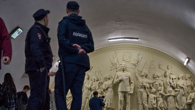 Policisté stojí před sochou, která ukazuje bývalého vůdce Sovětského svazu.  Pic: AP/Alexander Zemlianichenko