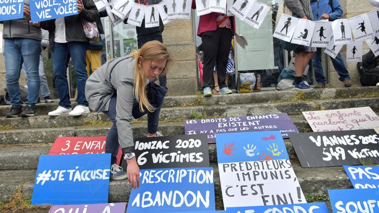 Lidé umístí plakáty během demonstrace před verdikt v soudním řízení s Joel Le Scouarnec, 74letý bývalý chirurg, obviněný z znásilnění a sexuálního napadení 299 dětí ve středu 28. května 2025 ve Vannes, Brittany, západní Francii. (AP Photo/Mathieu Pattier)