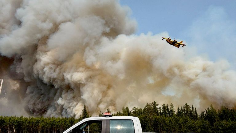 Vodní bombardér letí nad oblakem kouře z požáru poblíž pasu, Manitoba.  Pic: Reuters