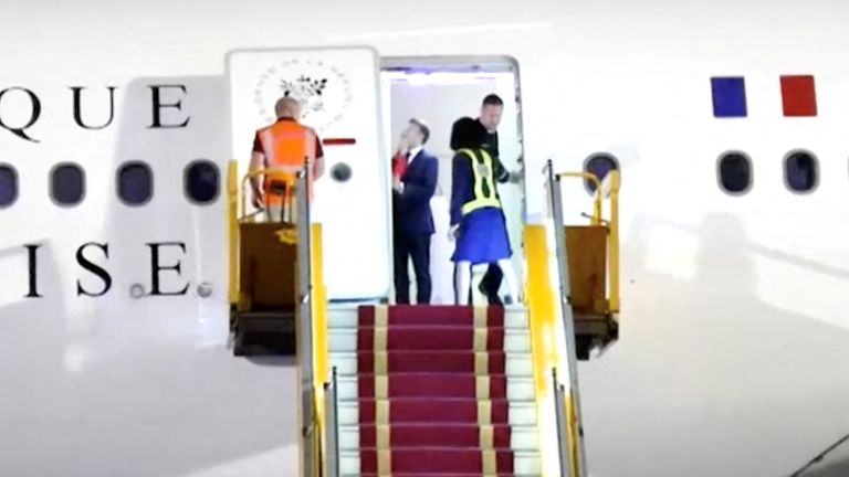 Francouzský prezident Emmanuel Macron stojí poblíž dveří letadla, jak se objeví ruka a odstrčí obličej pryč, v Hanoji ve Vietnamu, 25. května 2025, v tomto obrazovce z videa. Reuters TV/Via Reuters