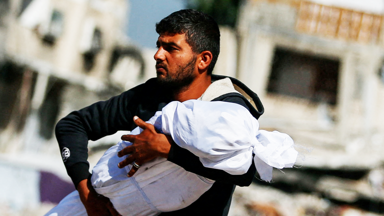 Palestinský muž nese tělo dítěte zabitého v izraelských úderech, v Jabalii, v pruhu Severní Gazy 16. května 2025. Reuters/Mahmúd Issa tpx obrazy dne
