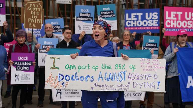 Doktor Geri Hignett protestuje proti změně zákona o asistovaném umírání, kromě protestujících prokazujících na podporu, mimo skotský parlament v Edinburghu, před debatou a hlasováním o asistovaném umírání pro vyléčení nemocných dospělých (Skotsko) později dnes. Datum obrázku: Úterý 13. května 2025.