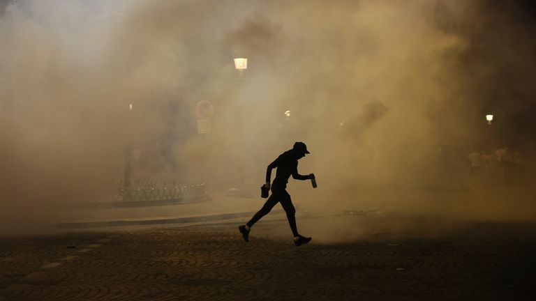 Muž prochází kolem slzů během incidentů po závěrečném fotbalovém zápase Ligy mistrů mezi Paříží Saint-Germain a Inter Milán. Pic: Ap