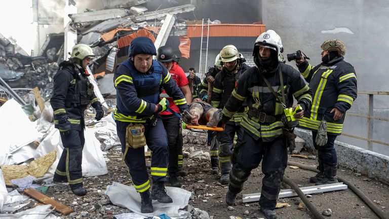 Záchranáři nesou zraněného obyvatele po první vlně ruského útoku na Charkiv.  Pic: Reuters/Sofiia Gatilova