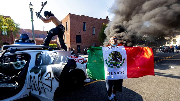 Demonstrátor zasáhne auto s vlastním pohonem s jeho skateboardem jako další popáleniny vzadu, během protestu proti federálním imigračním zametání, v centru Los Angeles v Kalifornii, USA, 8. června 2025. Reuters/Jill Connelly Tpx obrazy dne     