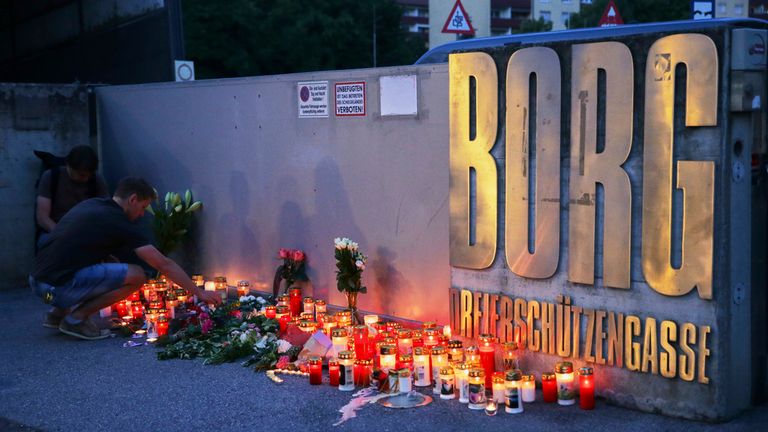 Muž umístí svíčku do vchodu do školy po smrtící střelbě v rakouském Grazu. Pic: AP Photo