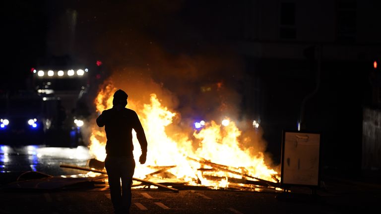 Osoba stojí před ohněm v ulici Ballymena. Pic: Pa