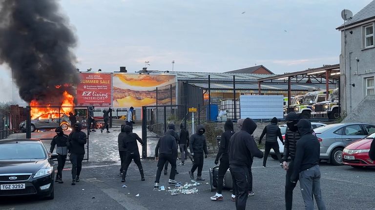Lidé sledují, jak vozidlo hoří během protestu v Ballymeně. Pic: Pa