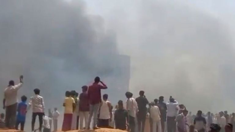 Lidé sledují, jak kouř stoupající poté, co letadlo havarovalo v Ahmedabad, Gujarat State, India, čtvrtek 12. června 2025. (Mohan Nakum přes AP)