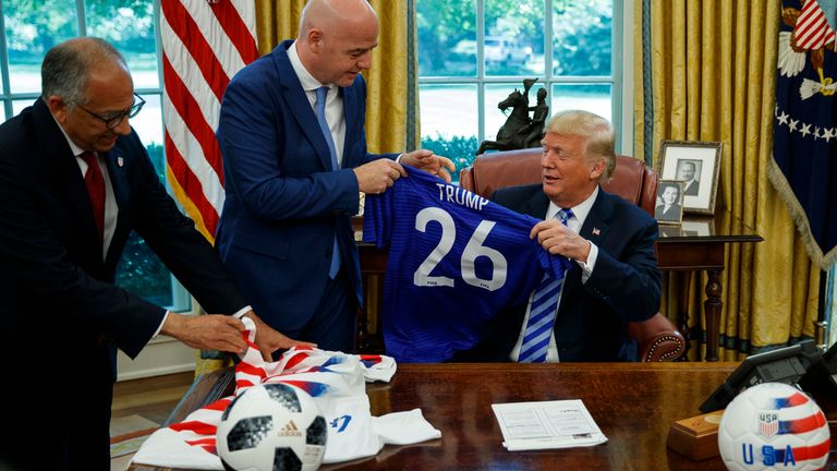 SOUBOR - Prezident fotbalové federace Spojených států Carlos Cordeiro, vlevo a prezident FIFA Gianni Infantino současný prezident Donald Trump s fotbalovými dresy během setkání v Oválné kanceláři Bílého domu, úterý 28. srpna 2018 ve Washingtonu. (AP Photo/Evan Vucci, soubor)