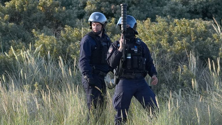 Francouzské úřady viděné na pláži ve Francii Gravelines, když se připravují na vystřelení slzného plynu u skupiny lidí považovaných za migranty. Pict