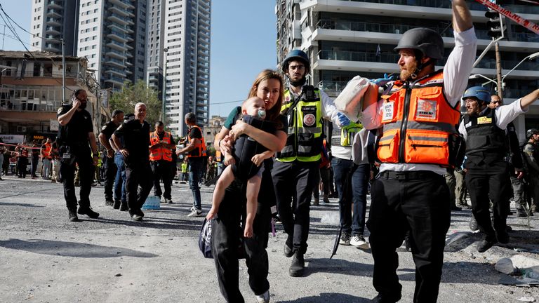 Žena nese své dítě na místě dopadu po raketovém stávce z Íránu na Izrael v Ramatu Gan v Izraeli.  Pic: Reuters