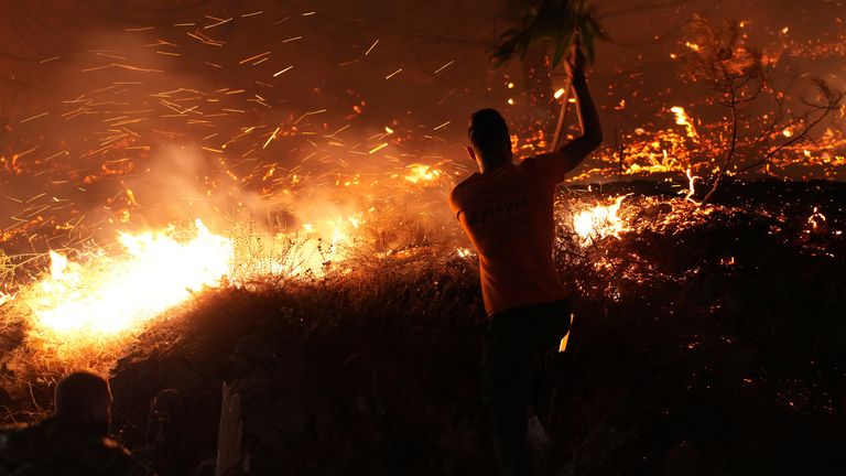 Muž používá pobočku k boji proti velkému pálení požárů v Kofinasu na ostrově Chios v Řecku.  Pic: Politischios/ap