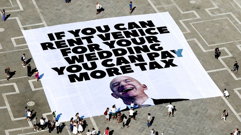Na zemi leží banner proti Jeffovi Bezosovi, umístění Itálie Greenpeace spolu s ostatními na náměstí St. Mark.  Pic: Reuters