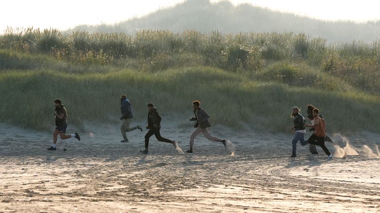 Lidé považovali za migranty, kteří se vynoří z keřů na pláži ve Francii ve Francii poté, co francouzské úřady vypálily slznou plyn. Datum obrázku