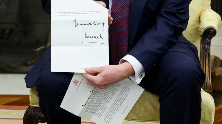 Americký prezident Donald Trump drží dopis britského krále Charlese, když se setkává s britským premiérem Keirem Starmerem (není na obrázku) v Oválné kanceláři v Bílém domě ve Washingtonu, DC, USA, 27. února 2025. Reuters/Kevin Lamarque.
