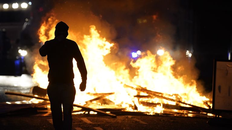 Osoba stojí před ohněm v ulici Ballymena. Pic: Pa