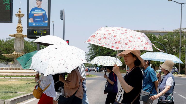 Lidé používají deštníky vedle teploměru zobrazujícího 47 stupňů Celsia během vlny Heat ve Španělsku Seville.  Pic: Reuters