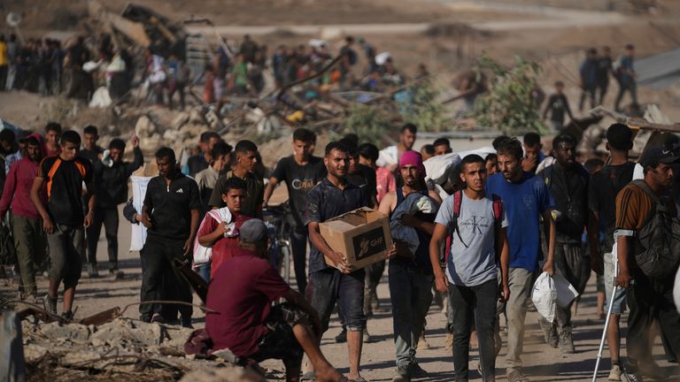 Palestinci nesou balíčky pomoci poblíž distribučního centra GHF v Khan Younis. Pic: AP/Abdel Kareem Hana