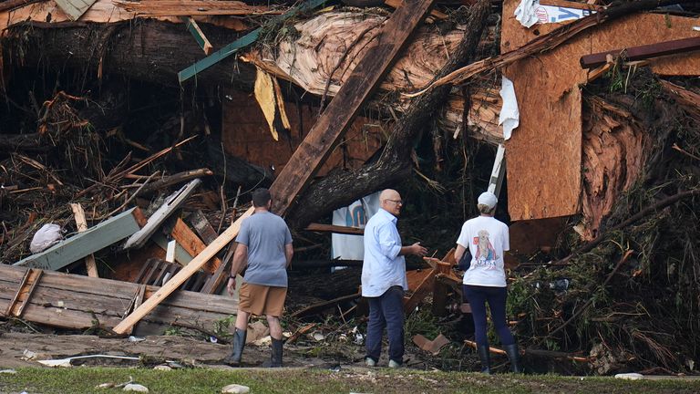 Lidé se dívají na úlomky na březích řeky Guadalupe po bleskové povodni zametli oblastí v sobotu 5. července 2025 v Hunt v Texasu. (AP Photo/Julio Cortez)