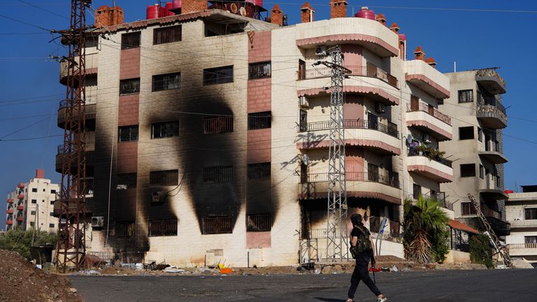 Po sektářských střetech chodí beduínský bojovník poblíž spálené budovy.  Pic: Reuters/Karam al-Masri