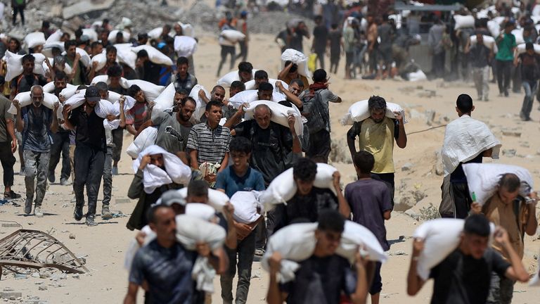 Palestinci nese pomocné zásoby, které vstoupily do Gazy přes Izrael, v Beit Lahia v severním pásmu Gazy, 27. července 2025. Reuters/Dawoud AB