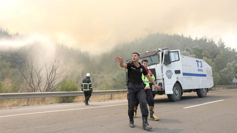 Policejní důstojník vyčistí oblast před příchodem hasičů během požáru poblíž Osmanelu, Turkey Pic: Reuters