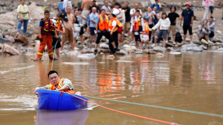 Muž sedí v plastové lodi, aby se přesunul do bezpečí poté, co zaplavily těžké srážky v Pekingském okrese Huairou. Pic: Reuters