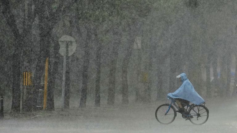 Muž jezdí na kole během silného deště v Pekingu v Číně. Pic: Ap
