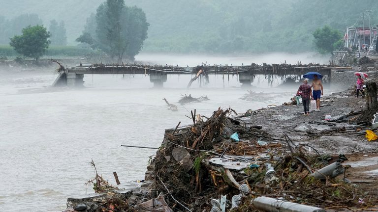 Lidé chodí po poškozeném mostě poté, co oblast zaplavila těžká srážky v okrese Huairou v Pekingu. Pic: Reuters