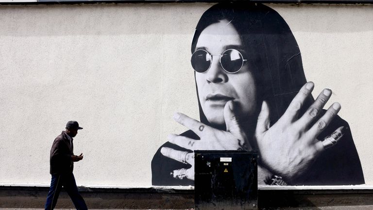 Muž prochází nástěnností Ozzy Osbourne, bývalého frontmana Black Sabbath, před pohřebním Cortege, v Birminghamu.  Pic Reuters