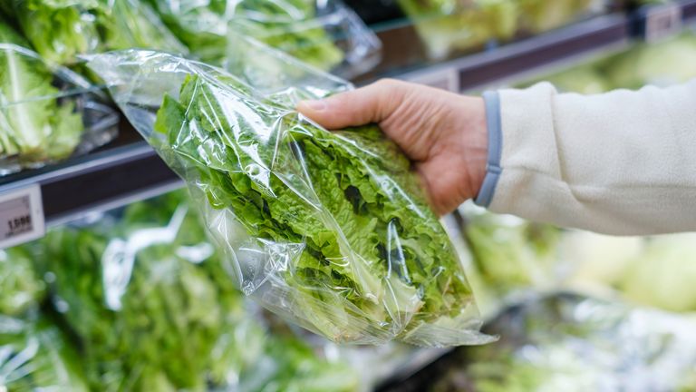 Obrázek: Istock. Muž ruka drží zelené salát listy v supermarketu detail