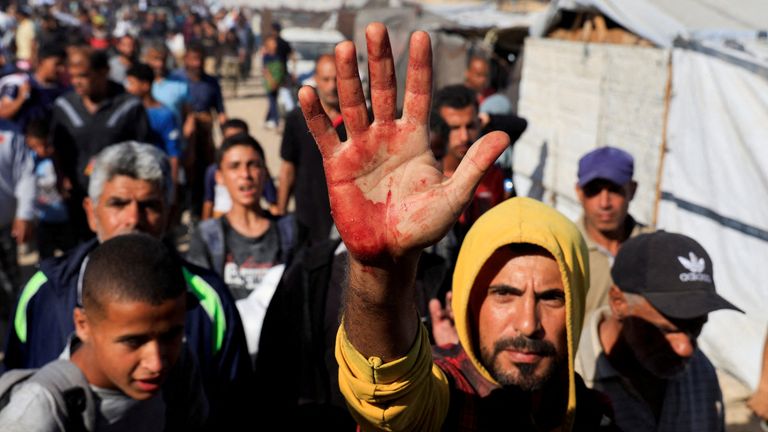 Palestinský muž, který nesl oběti, když lidé hledali pomoc z hlediska pomoci GHF. Pic: Reuters