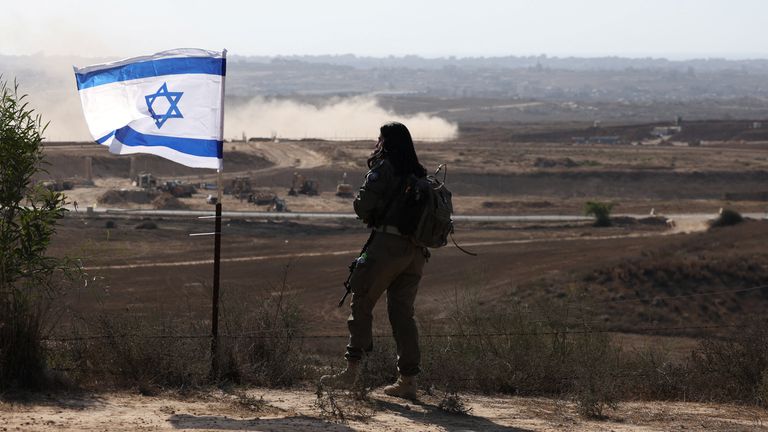 Izraelský voják, který stojí vedle izraelské vlajky, se dívá přes Gazu. Pic: Reuters