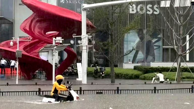 Doručovací jezdec se pohybuje po zaplavené silnici v Zhengzhou. Pic: Chinatopix/ap