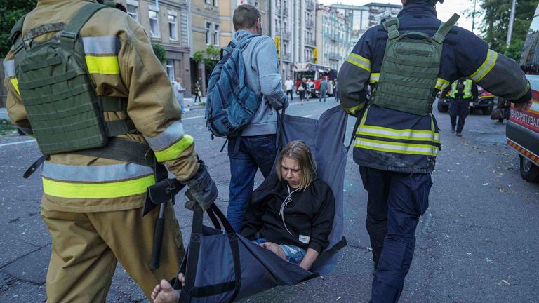 Záchranné dělníci nesou zraněnou ženu po ruské stávce na Kyjev na Ukrajině. Pic: Ap