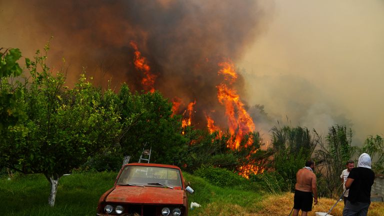 Lidé sledují požár na okraji Patras. Pic: Thanassis Stavrakis/Ap